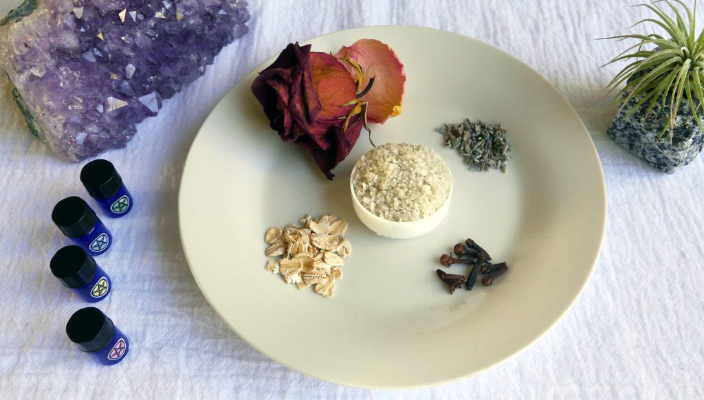 Salt circle bottles with salt, dried rose, lavender buds, whole cloves, and oats with an amethyst crystal.