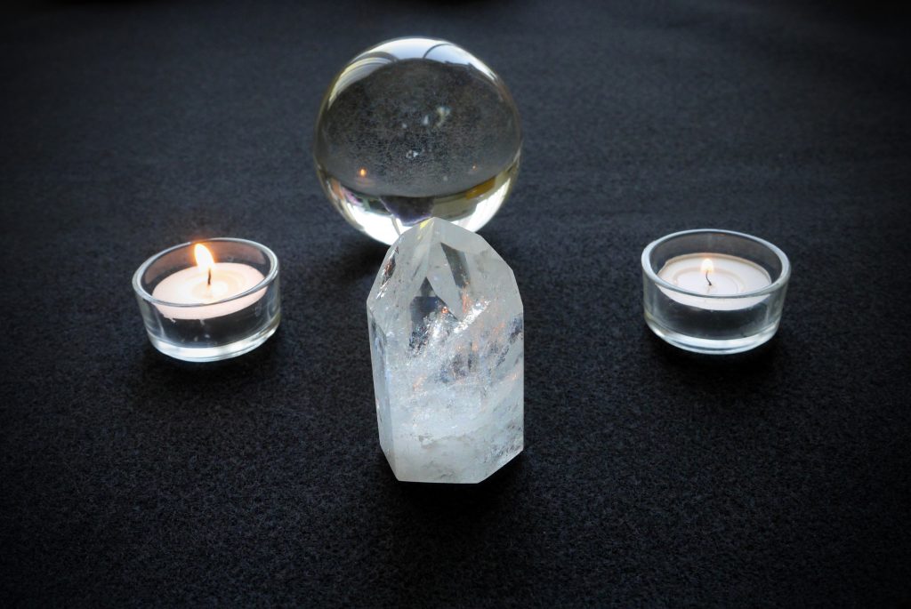 Clear quartz point, quartz crystal ball, candles