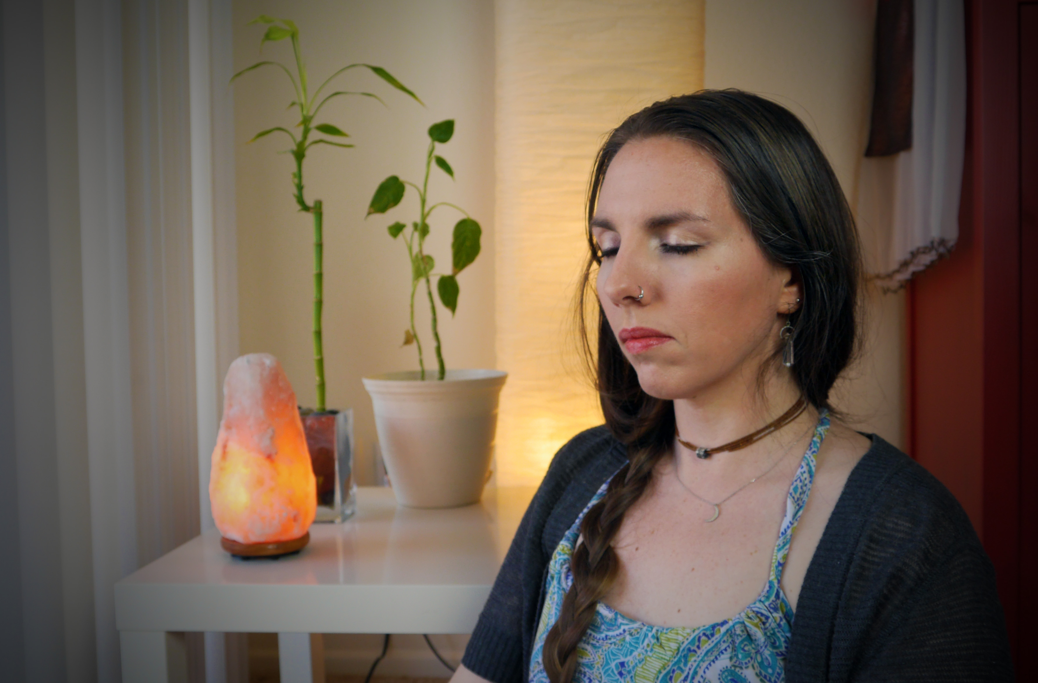 Woman meditating, calm, peaceful meditation with plants and Himalayan salt lamp.